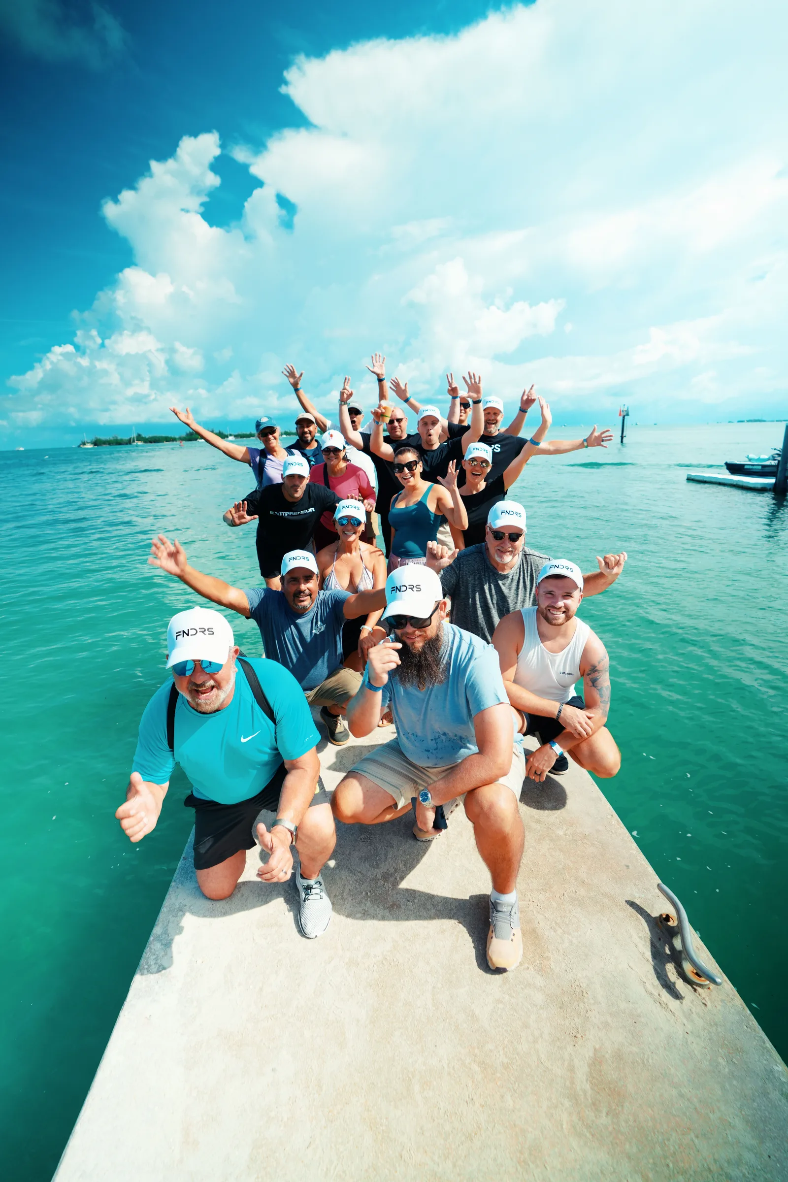 FNDRS founders on a pier in Key West, arms up, the water behind them