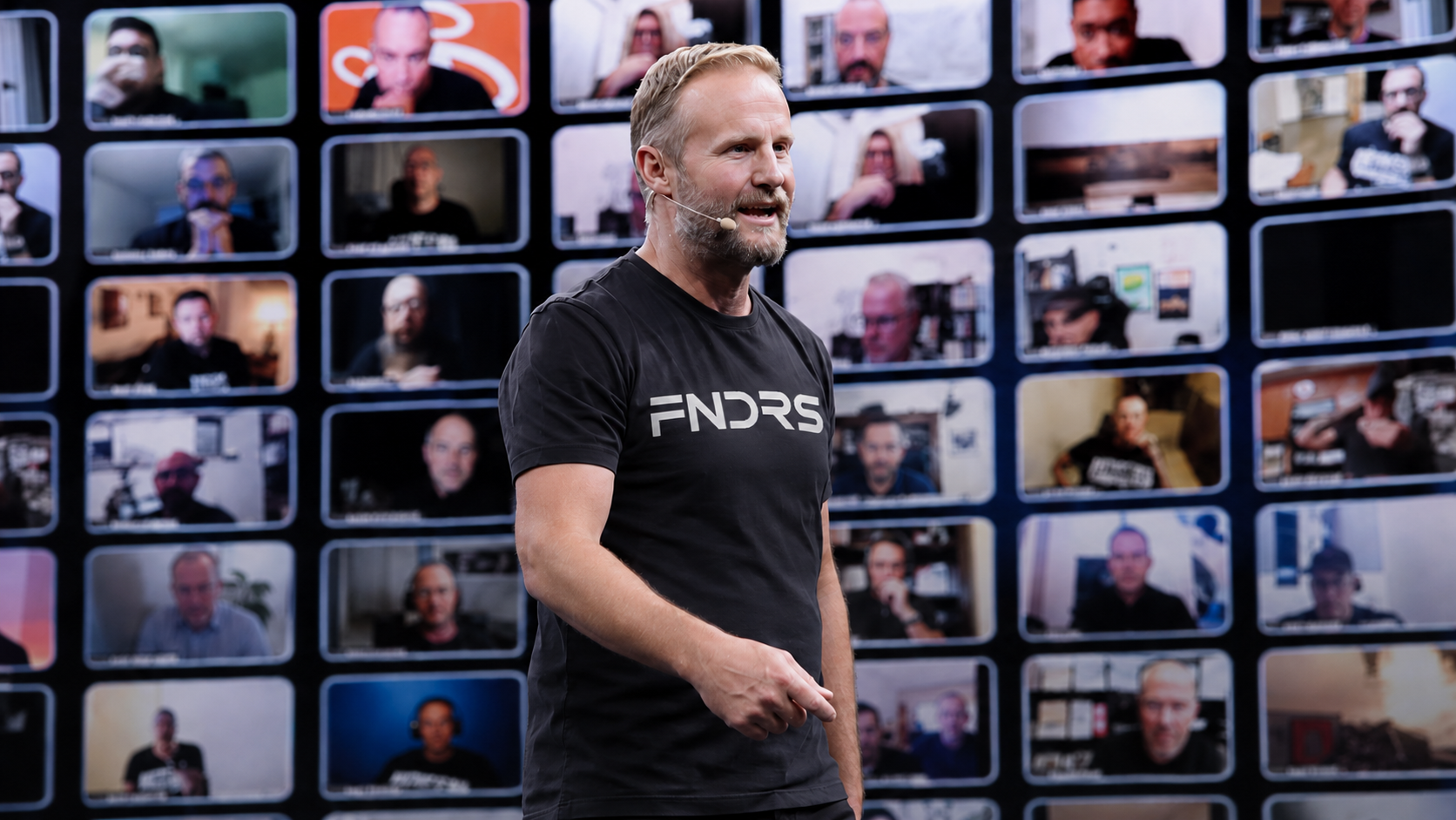 Nick Long on stage in a FNDRS shirt, a wall of founders on video behind him